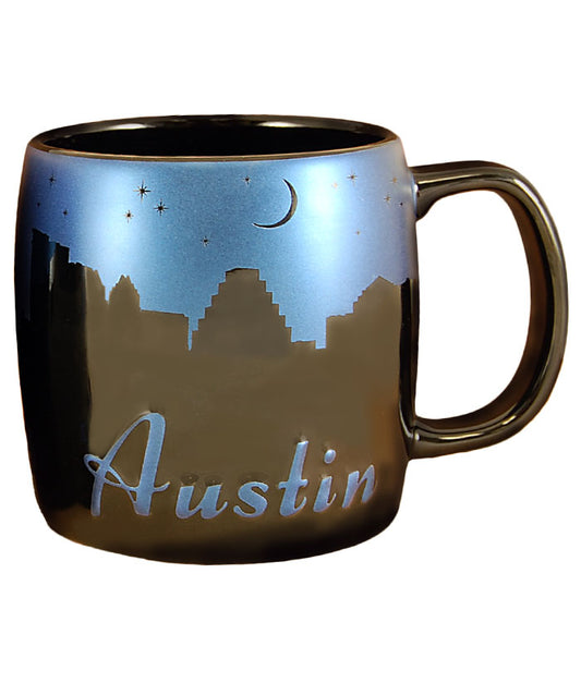 Enjoy your favorite hot beverage with this generously sized black Night Sky Mug. Features a metallic blue night sky with iconic silhouettes of your favorite Austin locations. Microwave and dishwasher safe. Holds 20 ounces