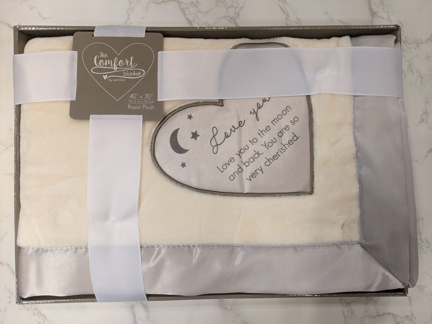 30" x 40" Royal plush blanket, packaged in a ribbon-wrapped open-faced box,  features silk heart detail and edging.  This text is printed onto embroidered heart the "Love You To The Moon And Back. You Are So Cherished" Neutral beige color.  A great gift to  welcome to the newborn baby to the family or for another loved one.
